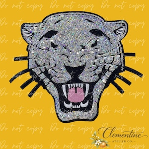 May include: A decorative patch featuring the head of a snarling panther. The panther is covered in shimmering silver sequins with black outlines, black whiskers, and a pink tongue visible inside an open mouth with white teeth and black gums.