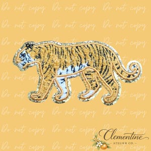 May include: Embroidered tiger patch in shades of gold, black, and white. The patch features a detailed design of a tiger walking, with a sequined border. The patch is likely for clothing or accessories.