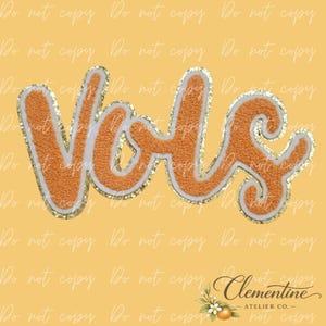 May include: A chenille patch featuring the word Vols in a cursive script. The letters are orange with a white border and a gold glitter outline. The patch has a textured, fuzzy surface and is presented against a solid yellow background.