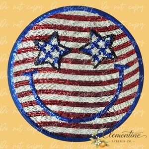 Op de afbeelding: Een ronde patch met een lovertjesontwerp van een smiley met rode en witte horizontale strepen. De ogen bestaan uit twee blauwe sterren met witte accenten en een grote, gebogen blauwe lijn van lovertjes vormt een brede glimlach.