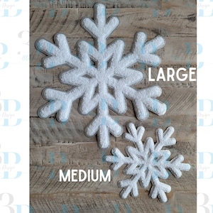 May include: Two white snowflake-shaped patches with a textured, fuzzy surface and a silver-colored border. The larger patch is labeled with the text LARGE, and the smaller patch is labeled with the text MEDIUM, indicating two distinct sizes.