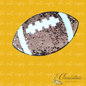 May include: A football-shaped patch covered in shimmering bronze sequins. The design features white stitched-style accents across the center and two white vertical stripes near the ends, creating the classic appearance of an American football.