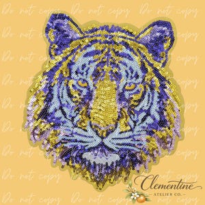 May include: A sequined tiger head design in shades of gold, purple, and light blue. The tiger's face is centered, with detailed eyes and a textured appearance. The design is set against a light orange background.