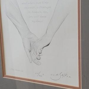 May include: A framed black and white ink drawing of two hands holding each other. The text above the hands reads: and when our time on earth is through in heaven, too, you will have my hand. The title The Promise and a signature are visible.