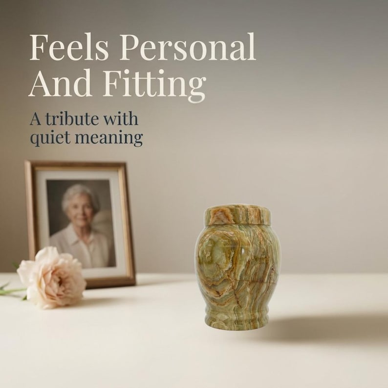 May include: A green and brown marbled stone urn with a matching lid. The text "Feels Personal And Fitting" and "A tribute with quiet meaning" appears above a framed photograph of a person and a pale pink flower on a light surface.