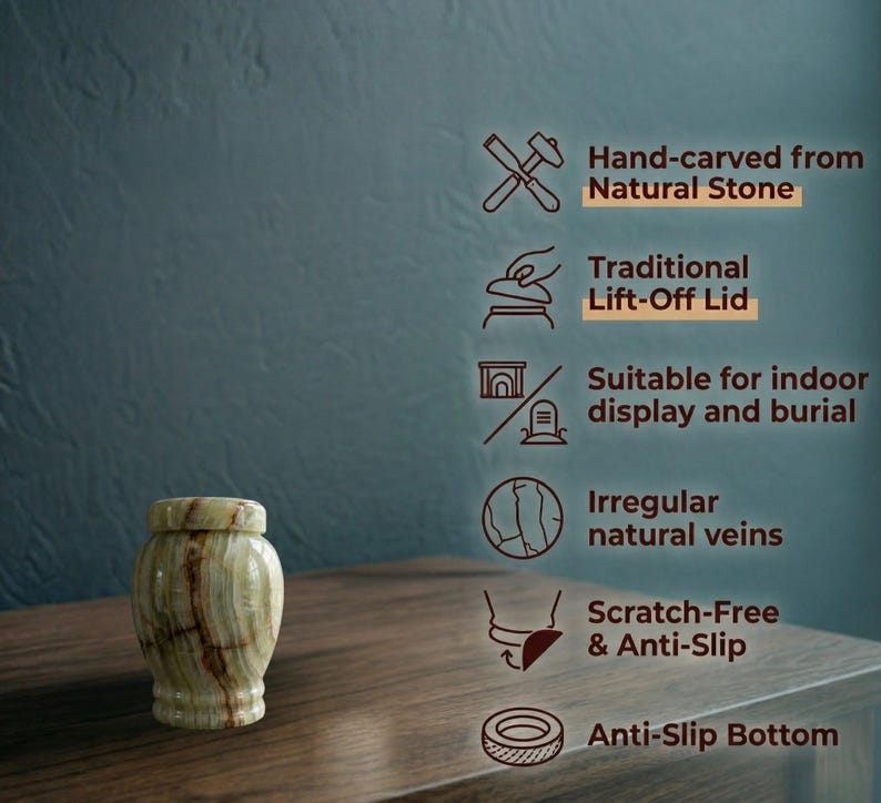 May include: A small, cylindrical natural stone urn featuring light green and brown veining with a matching lift-off lid. Text on the right lists features: Hand-carved from Natural Stone, Traditional Lift-Off Lid, Suitable for indoor display and burial, Irregular natural veins, Scratch-Free & Anti-Slip, and Anti-Slip Bottom.