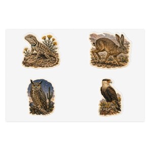 Peut inclure: Une planche d'autocollants présentant quatre illustrations distinctes : un lézard brun sur un rocher avec des fleurs jaunes, un lièvre brun courant dans un paysage désertique, un hibou brun perché sur une branche la nuit avec un cactus, et un caracara.