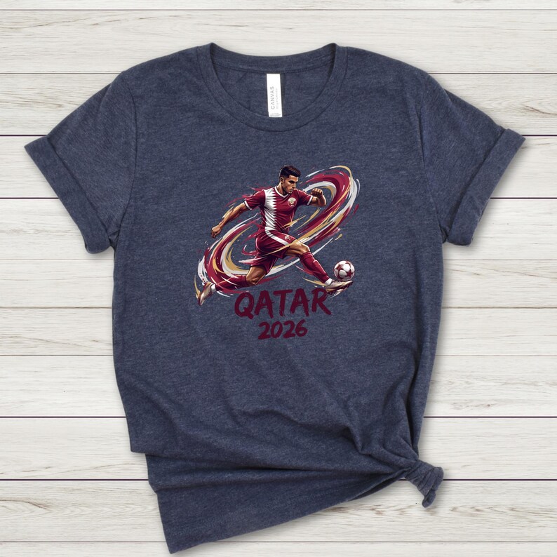 A dark blue t-shirt with a graphic design depicting a soccer player kicking a ball, along with the text "QATAR 2026" printed on it.