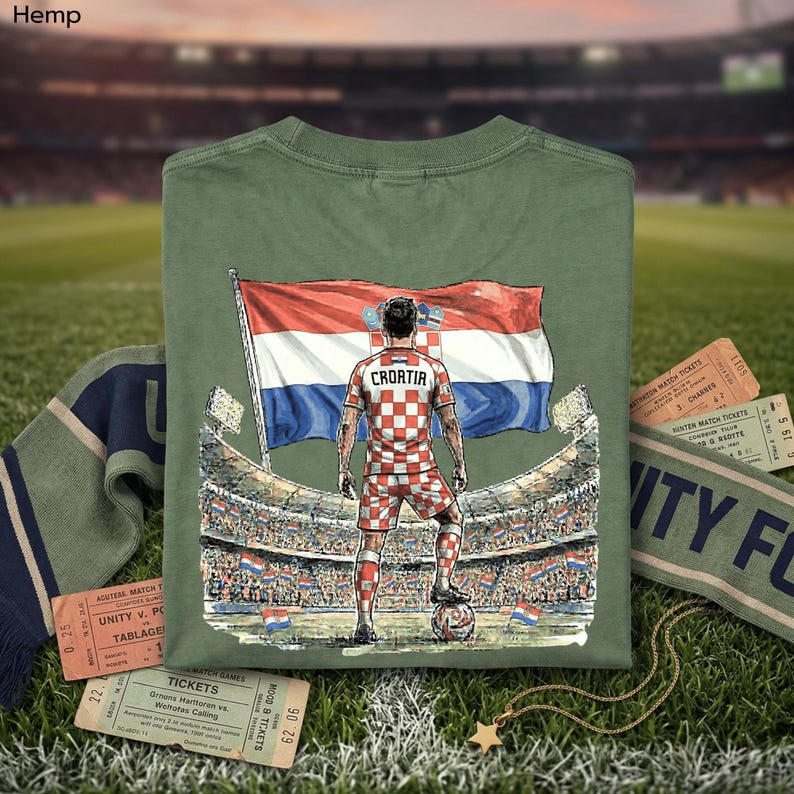 a green t-shirt with a graphic of a soccer player standing in front of a stadium, holding a flag, and wearing a red and white checkered uniform.