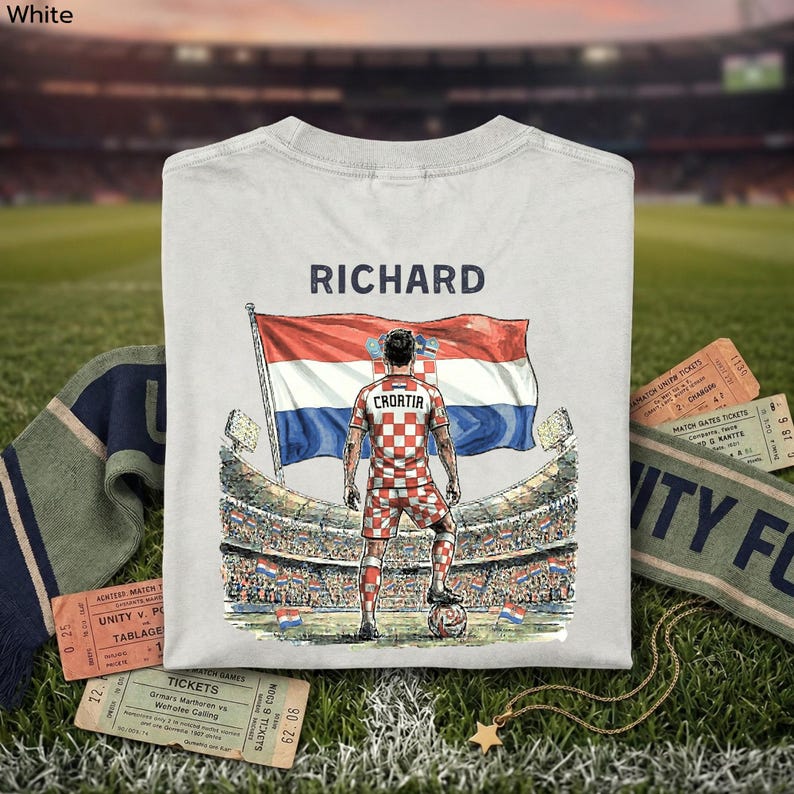 A white t-shirt with a graphic design depicting a soccer player standing in front of a stadium, holding a flag with the name 'Richard' and the word 'Croatia' written on it.