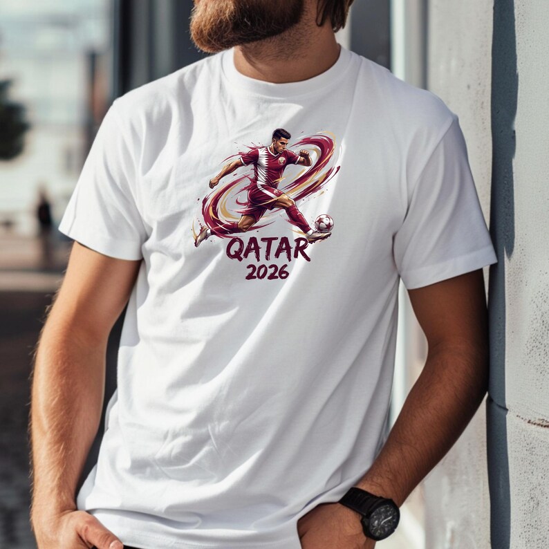 A man wearing a white t-shirt with a graphic of a soccer player and the text "QATAR 2026" printed on it.