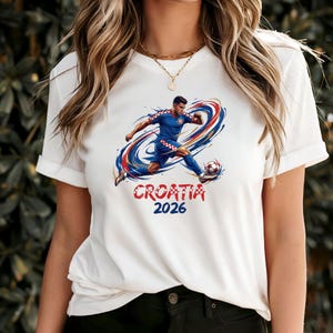 A white t-shirt with a graphic of a soccer player in action, along with the text "Croatia 2026" printed on it.