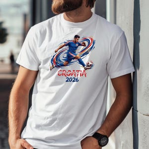 A white t-shirt with a graphic design depicting a soccer player in action, along with the text "Croatia 2026".