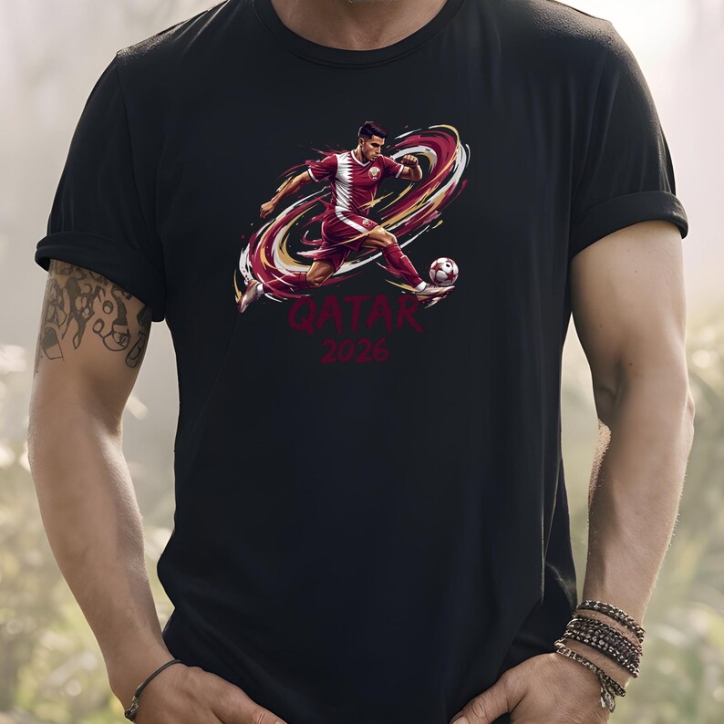 A person wearing a black t-shirt with a graphic of a soccer player kicking a ball, along with the text "QATAR 2026" printed on it.