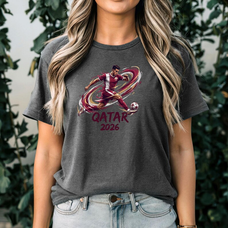 A woman wearing a grey t-shirt with a graphic of a soccer player kicking a ball, along with the text "QATAR 2016".