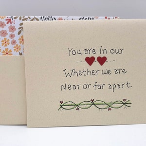 May include: A beige card with the text "You are in our hearts whether we are near or far apart." The card has two red hearts and a green vine with small red hearts.