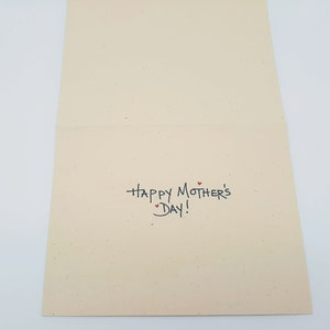 May include: A blank card with the text "Happy Mother's Day!" written in black ink. There are three small red hearts above the text.