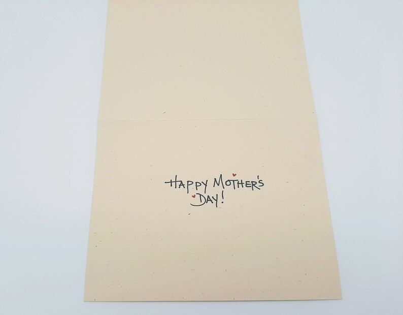 May include: A blank card with the text "Happy Mother's Day!" written in black ink. There are three small red hearts above the text.