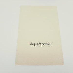 May include: A blank white card with the text "Happy Birthday!" written in black ink. There are small red hearts around the text.