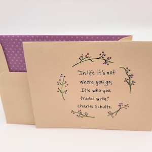 May include: A beige card with a quote about travel and friendship. The quote reads "In life it's not where you go; It's who you travel with."  The quote is attributed to Charles Schultz.