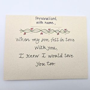 May include: A card with a handwritten message that reads "When my son fell in love with you, I knew I would love you too." The card is decorated with a green vine with red hearts.