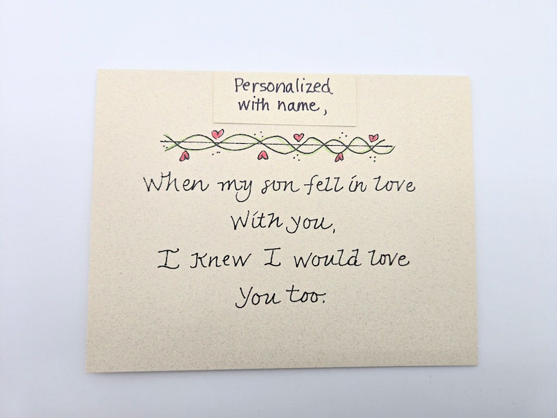 May include: A card with a handwritten message that reads "When my son fell in love with you, I knew I would love you too." The card is decorated with a green vine with red hearts.