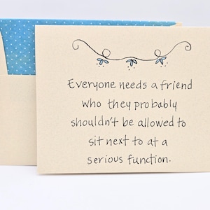 May include: A beige card with a blue envelope. The card has a handwritten message that reads "Everyone needs a friend who they probably shouldn't be allowed to sit next to at a serious function."