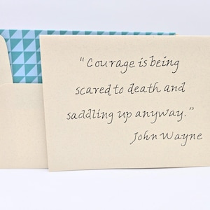 May include: A beige card with a quote by John Wayne: "Courage is being scared to death and saddling up anyway."