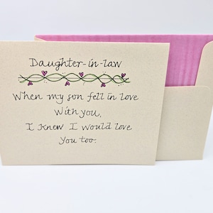 May include: A card with a handwritten message that reads "Daughter-in-law When my son fell in love With you, I knew I would love You too." The card has a green vine with pink hearts along the top.