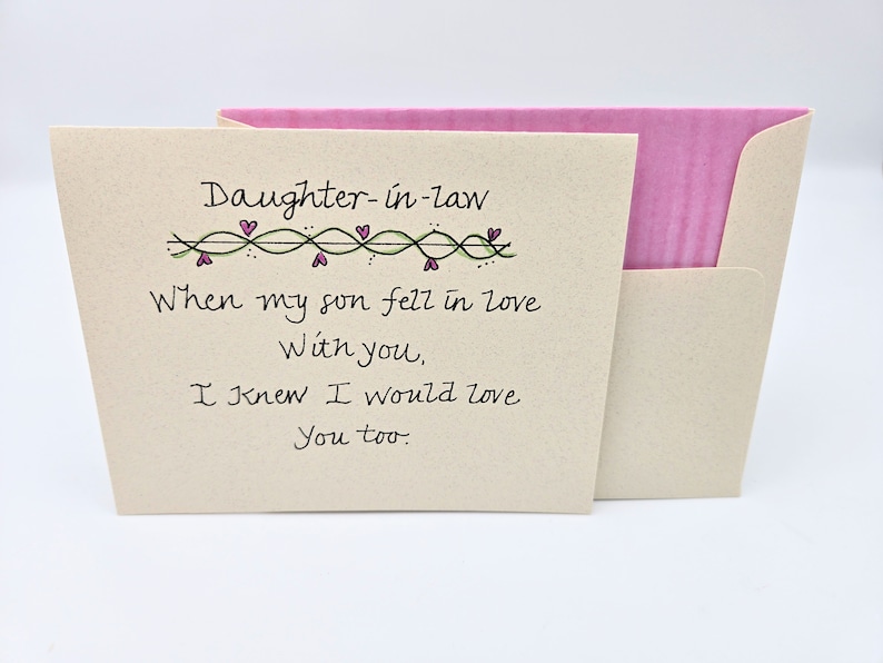 May include: A card with a handwritten message that reads "Daughter-in-law When my son fell in love With you, I knew I would love You too." The card has a green vine with pink hearts along the top.