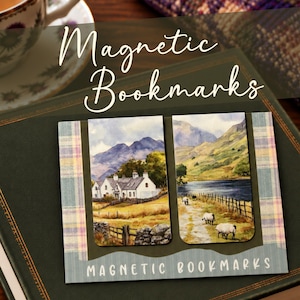 May include: Two rectangular magnetic bookmarks featuring watercolour-style landscape illustrations of white cottages, rolling mountains, a lake, and sheep grazing in a field. The bookmarks are displayed on a card with the text MAGNETIC BOOKMARKS.