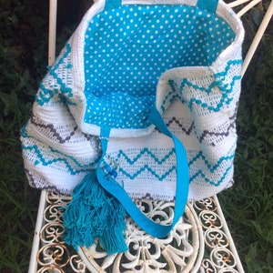 Pode incluir: Sacola tote de croch&ecirc; branca com forro de bolinhas azuis e brancas. A sacola tem um tassel azul e uma al&ccedil;a de fita azul.