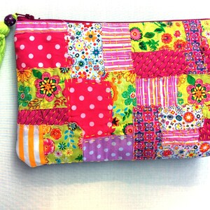 May include: A patchwork fabric zippered pouch with a bright green tassel. The pouch is made of various colourful fabrics with floral and geometric patterns.