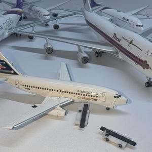 Könnte beinhalten: Ein Set aus drei Keramikbechern mit gesprenkelter, matter Oberfläche. Die Becher sind in Creme-, Hellgrau- und Dunkelgrautönen gehalten. Jeder Becher hat ein schlichtes, minimalistisches Design, ideal für Kaffee oder Tee.