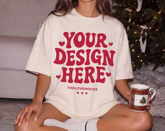 May include: An off-white short-sleeve t-shirt featuring the red text "YOUR DESIGN HERE" in a bold, wavy font, accented with small red hearts. The shirt also displays the text "THELOVEMOCKS" in a smaller, simple red font below the main design.