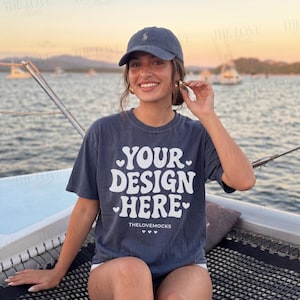 Puede incluir: Una camiseta azul marino con el texto blanco "YOUR DESIGN HERE" y una gorra de béisbol azul marino. La camiseta tiene un aspecto vintage. El texto "THELOVEMOCKS" está impreso en la parte inferior de la camiseta.