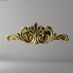 May include: A gold-colored, ornate decorative element with a symmetrical design. The piece features a central floral motif with swirling, scroll-like details extending outwards. The overall shape is a horizontal, curved form.