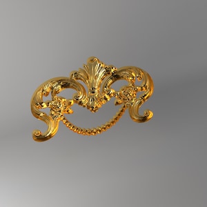 May include: A gold-coloured metal drawer pull featuring an ornate, symmetrical design with scrolling acanthus leaf motifs, two small floral accents on the sides, and a central drop handle with a textured, beaded edge finish.
