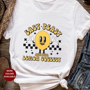 K&ouml;nnte beinhalten: Wei&szlig;es T-Shirt mit einer gelben Cartoon-Zitrone mit dem Text "Easy Peasy Lemon Squeezy".