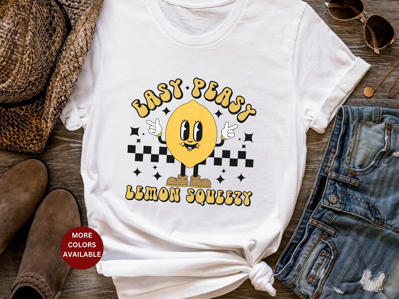 K&ouml;nnte beinhalten: Wei&szlig;es T-Shirt mit einer gelben Cartoon-Zitrone mit dem Text "Easy Peasy Lemon Squeezy".