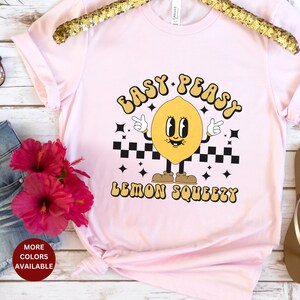 K&ouml;nnte beinhalten: Pinkes T-Shirt mit einem gelben Zitronen-Motiv und dem Text "Easy Peasy Lemon Squeezy".