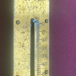 Peut inclure: Balance Landers Improved No. 2 vintage, fabriqué à New York. La balance de couleur laiton a un crochet et un anneau. Elle mesure jusqu'à 25,4 kg. L'échelle montre des signes d'usure.