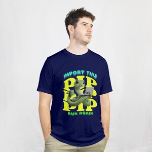 May include: Navy blue t-shirt with a cartoon snake holding a laptop and a coffee cup. The shirt has the text "IMPORT THIS PIP RUN AGAIN" in yellow and teal. The snake is green and the laptop is gray.