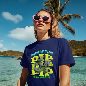 May include: Navy blue t-shirt featuring a green snake graphic holding a laptop and a coffee cup. The text on the shirt says "IMPORT THIS PIP PIP PIP RUN AGAIN" in green and light blue. The background shows a tropical beach scene with palm trees and blue skies.