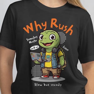 May include: Black t-shirt with a cartoon turtle wearing headphones and a denim jacket, holding a laptop. The shirt has the text "Why Rush" and "Slow but steady". The turtle is green, wearing a yellow shirt and brown trousers.