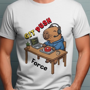 Może przedstawiać: Biała koszulka z kreskówkową kapibarą w zestawie słuchawkowym i niebieskiej bluzie z kapturem, siedzącą przy biurku z laptopem i przyciskiem odtwarzania. Słowa "GIT PUSH Force" są wydrukowane nad i pod kapibarą w kolorze czerwonym i czarnym.