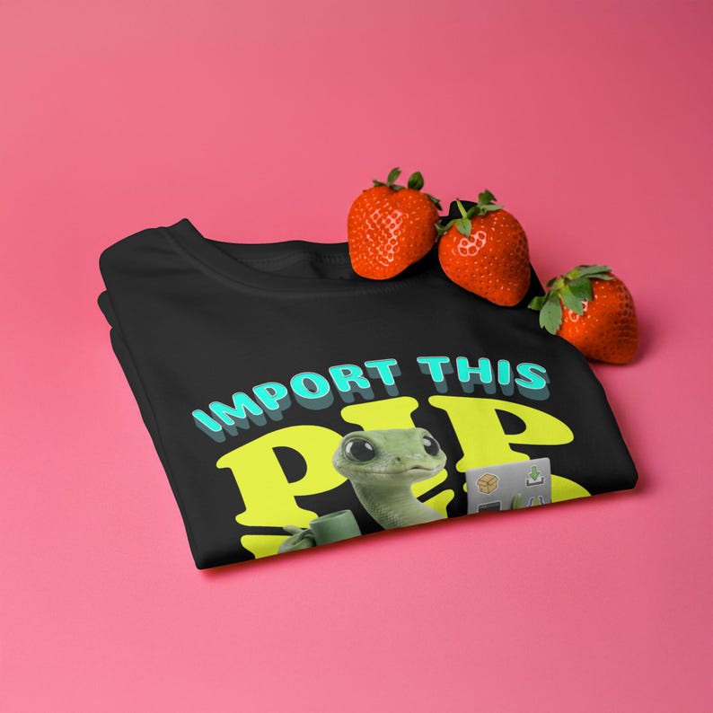 May include: Black t-shirt with the text "IMPORT THIS PEEP" in turquoise and yellow. The graphic features a cartoon gecko with a coffee cup and a laptop. Three fresh strawberries rest on the shirt against a pink background.