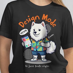 Pode incluir: Camiseta preta com um desenho animado de um cão Samoyed usando uma camisa havaiana e shorts, segurando um tablet e uma caneta. A camisa tem as palavras "Design Mode" e "It just feels right". O cão está sorrindo.