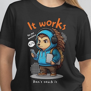 May include: Black t-shirt featuring a cartoon hedgehog wearing a blue hoodie and headphones, holding a phone and a laptop. Text reads "It works" and "Don't touch it". The hedgehog has a backpack and is looking at the phone with a serious expression.