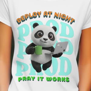 May include: White t-shirt featuring a cartoon panda holding a green mug and a laptop. The shirt has the text "DEPLOY AT NIGHT, PRAY IT WORKS" in orange and green, with the word "POD" in a teal color.